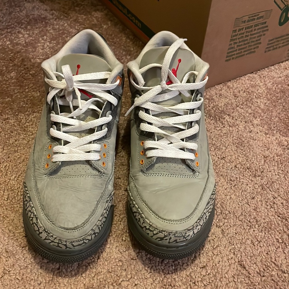 Grey and white Jordans in a size 9.5. With orange & red on the symbol